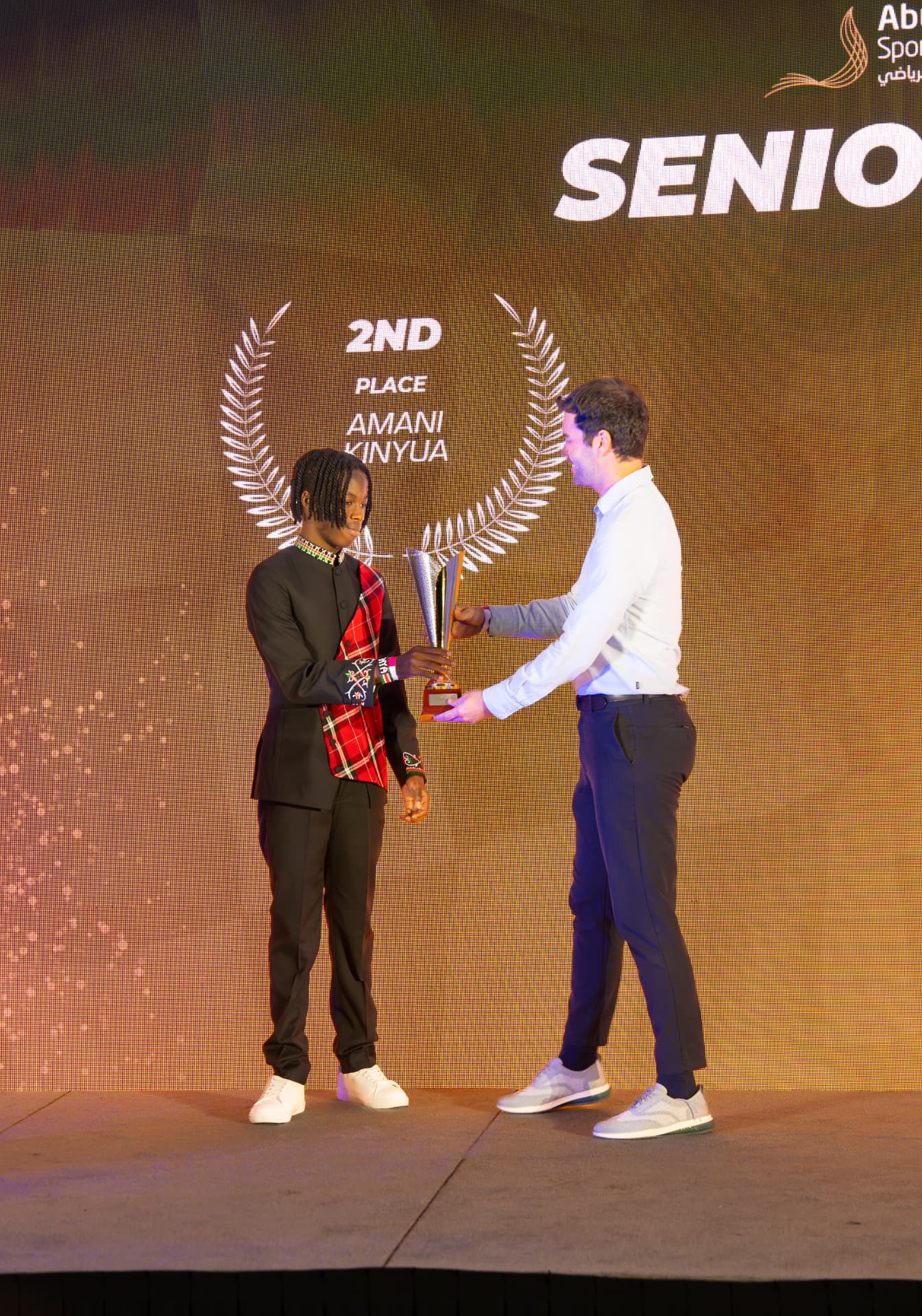 Amani receiving a second place trophy on stage